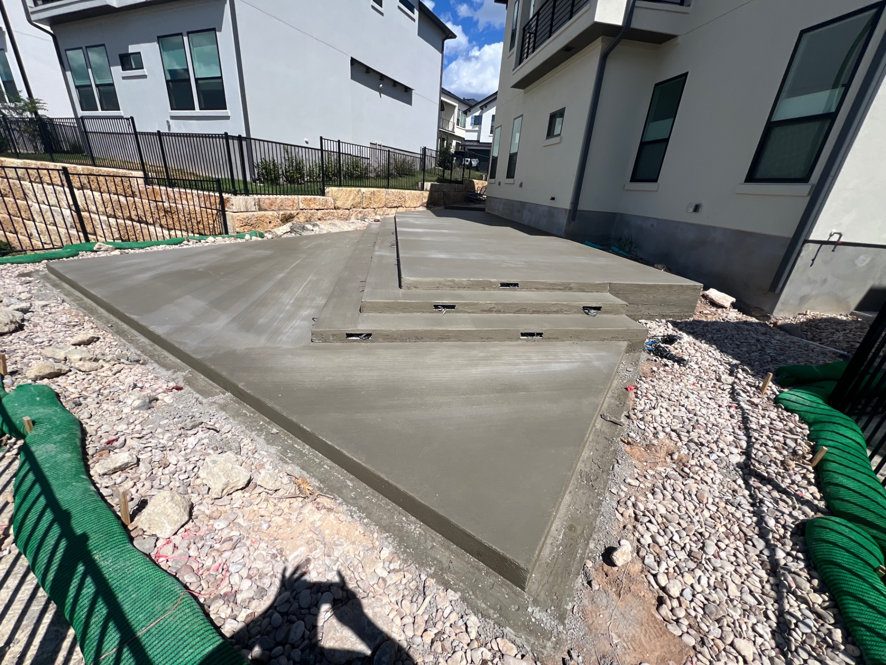 Custom patio with integrated steps and smooth troweled finish between modern homes
